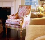 Ornate upholstered armchair with pink floral fabric in a living room.