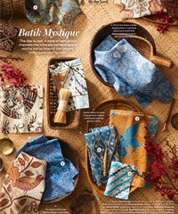 Assorted Batik textiles in blue, gold, and cream are arranged in woven baskets and on a table.