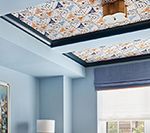 Blue room with patterned ceiling and window with shades.