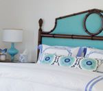 Bed with turquoise headboard, white bedding, and blue accent pillows.