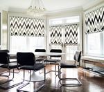 Dining room with black and white patterned window shades, white table, and black chairs.