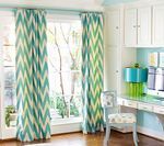 Teal and white chevron-patterned curtains in a light blue room with a desk and cabinets.