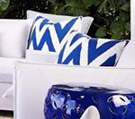White couch with blue and white patterned pillows; blue ceramic side table.