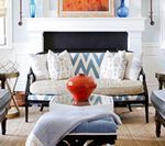 Living room with sofa, blue patterned pillows, and a red vase on a square ottoman.