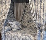 Canopied daybed with blue and white floral patterned fabric and pillows.