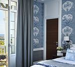 Bedroom with blue patterned wallpaper, French doors, and a dark brown door.