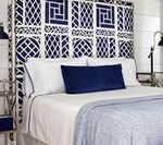 Blue and white patterned headboard over a bed with white and blue bedding, and a decorative pillow.
