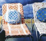 Two patterned lounge chairs with round pillows against a blue backdrop.