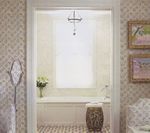 Bathroom view through doorway with a bathtub, decorative stool, and floral wallpaper.