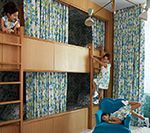 Children play in bunk beds with patterned curtains.