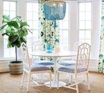 Dining room with white table, chairs, blue chandelier, and floral curtains.