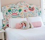 Bed with white linens, floral headboard, decorative pillows.