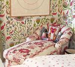 Chaise lounge with floral pattern, against matching wallpaper, cushions, art print.