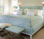 Spacious bedroom with a large bed in blue floral patterned fabric, two matching benches at foot.