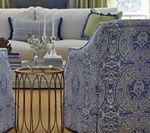 Blue patterned armchair in a living room with a white couch and decorative pillows.