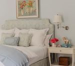 Bedroom with upholstered headboard, white bedding, and nightstand with lamp.