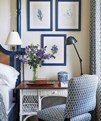 Bedroom nook with desk and blue-framed art above, featuring a blue and white patterned chair and blue accents.