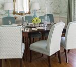 Elegant dining room with a dark wooden table and light blue chairs, set for a meal.