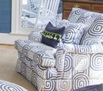 Upholstered chair with swirling blue and gray pattern; navy pillow with green tassels.
