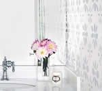 Bathroom with white walls and countertops, flowers in a black vase, and a silver faucet.