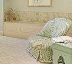 Armchair with green and white chevron pattern in a spa-like room with marble accents and a green table.