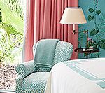 Armchair by window with pink curtains and teal accents.