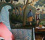 Bed with blue chevron headboard, pink pillow, and a mural showing figures in a forest.