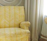 Yellow patterned armchair near a window with beige curtains.