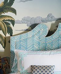 Blue chevron patterned headboard with white and blue pillows, against a tropical mural.