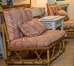 Rattan furniture with red and white patterned cushions and pillows, indoors.