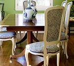 Dining room table with ornate chairs; vase of flowers in the center.