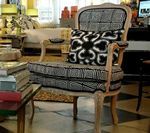 Upholstered chair with black and white patterned fabric and decorative pillow. Interior setting.
