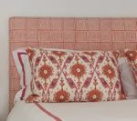 Pink woven headboard with floral patterned pillow.