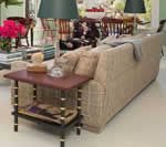 Living room with woven beige sofa, end table, lamps, and partial view of a dining table with chairs.