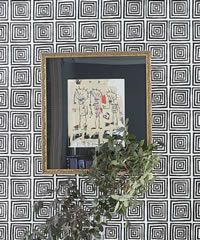 Mirror with gold frame, reflecting artwork of stick figures, against black and white square patterned wallpaper.