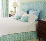 Bedroom with blue chevron headboard, bed skirt, pillows, and white bedding.