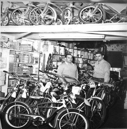 A black and white photo of two men in a bicycle shop