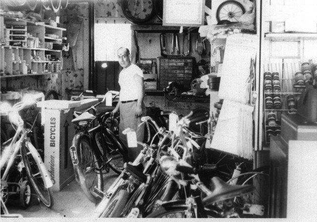 A black and white photo of a man in a bicycle shop