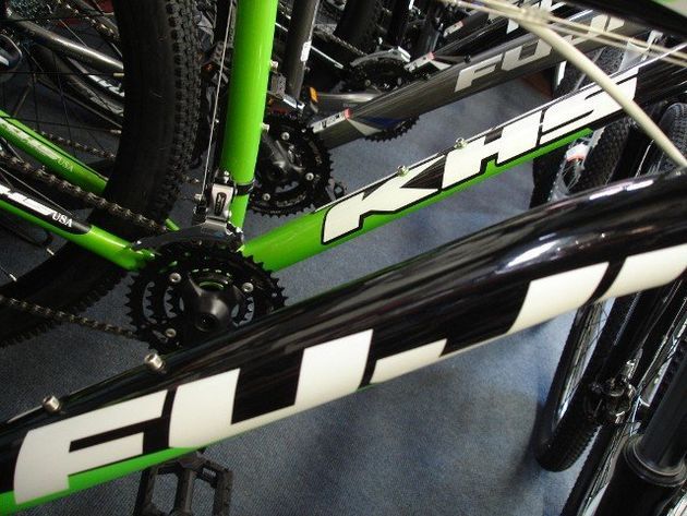 A green and black fuji bicycle is sitting on the floor