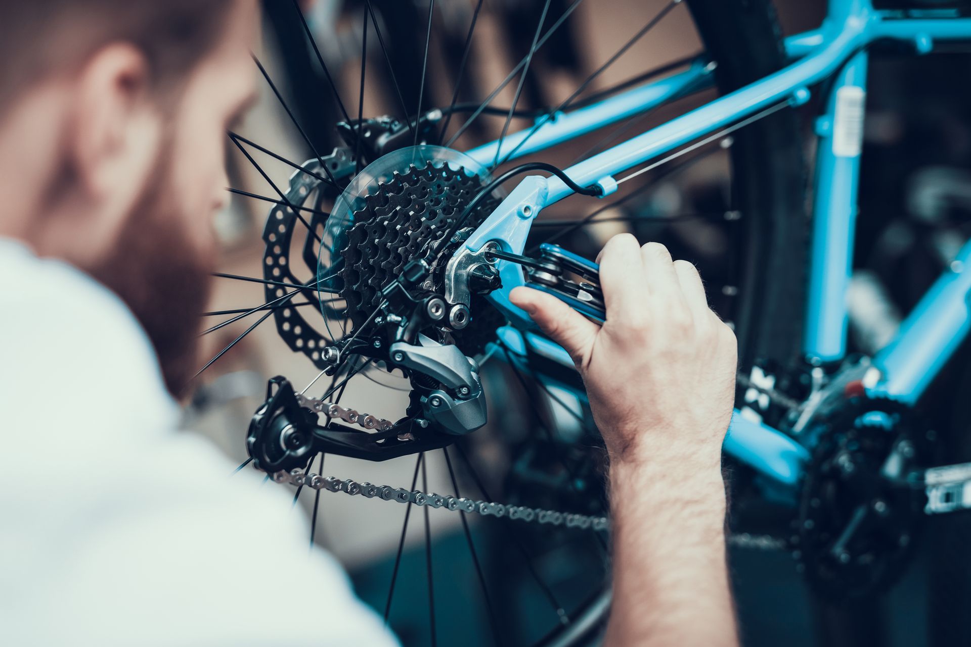 A man is working on a blue bicycle in a garage.