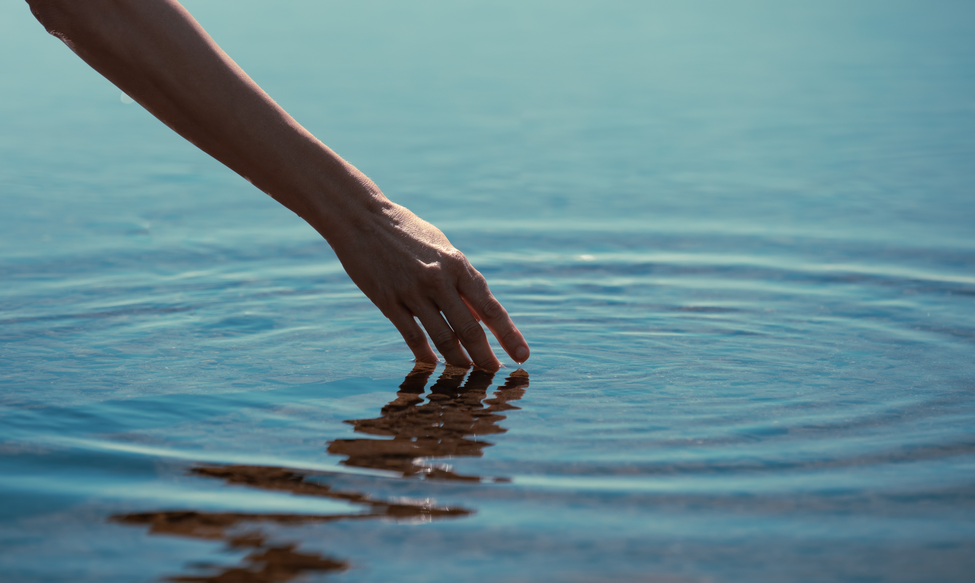 A close up of a person 's hand touching the water.