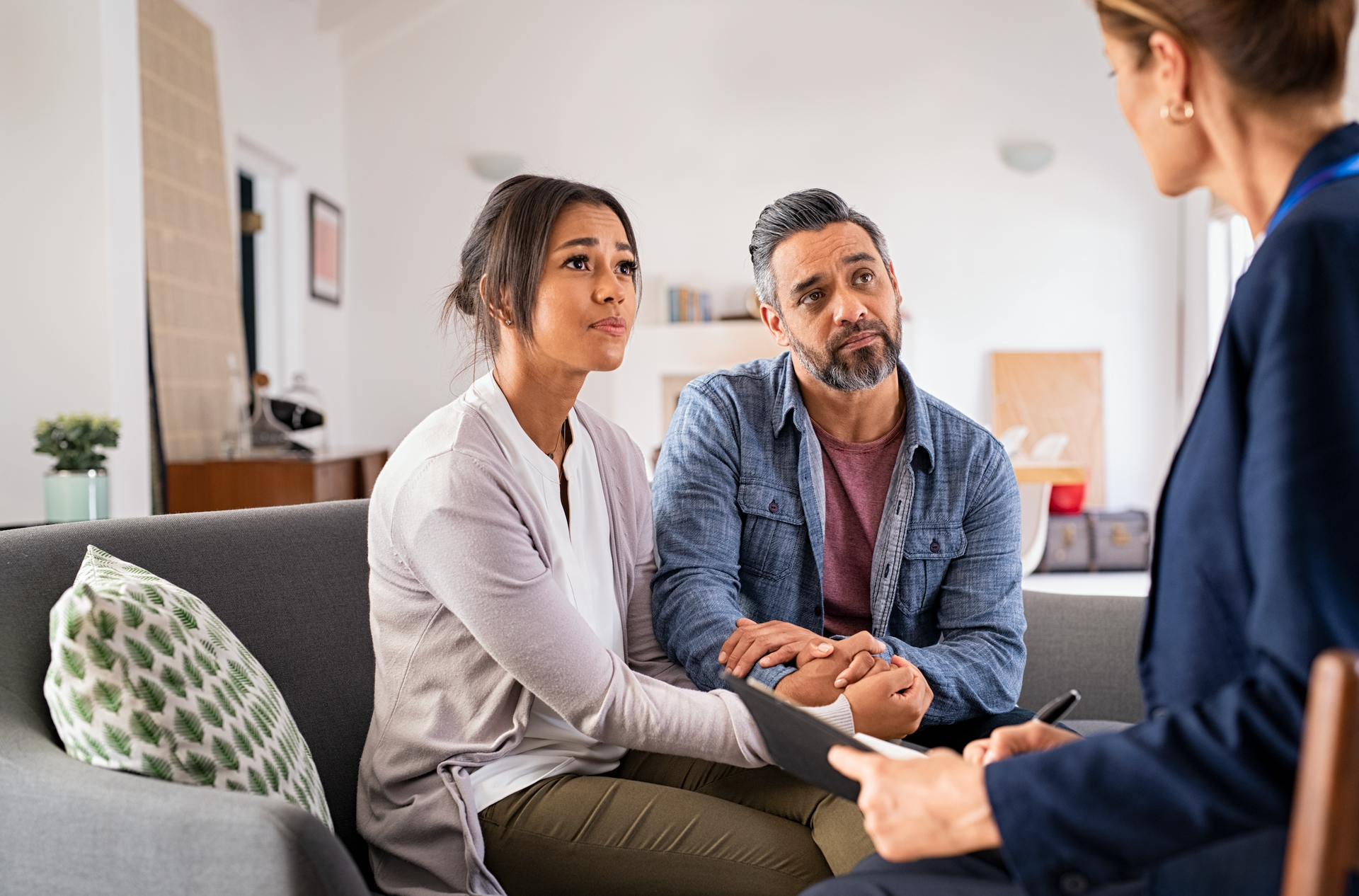 A man and a woman are sitting on a couch talking to a woman.