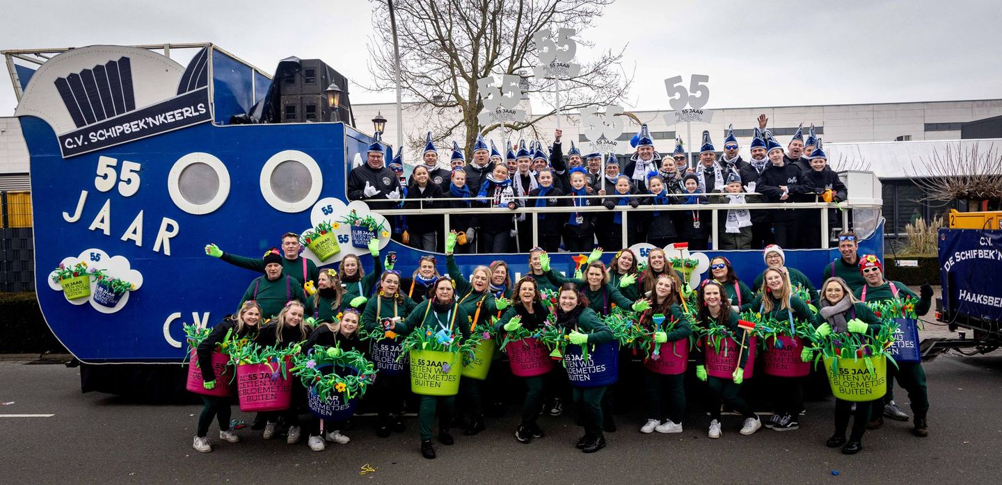 Mensen in kostuums op een praalwagen met de woorden 