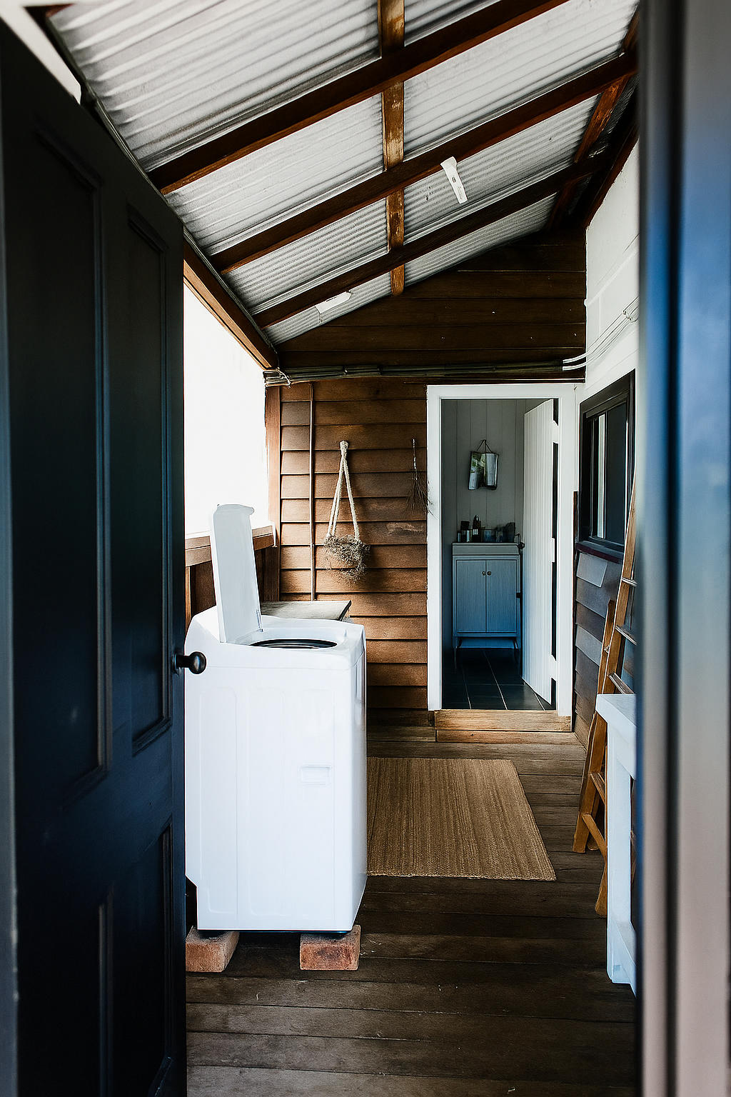 A black door is open to a kitchen with a stove and a sink.