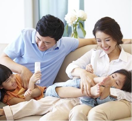 A family is sitting on a couch playing with their children