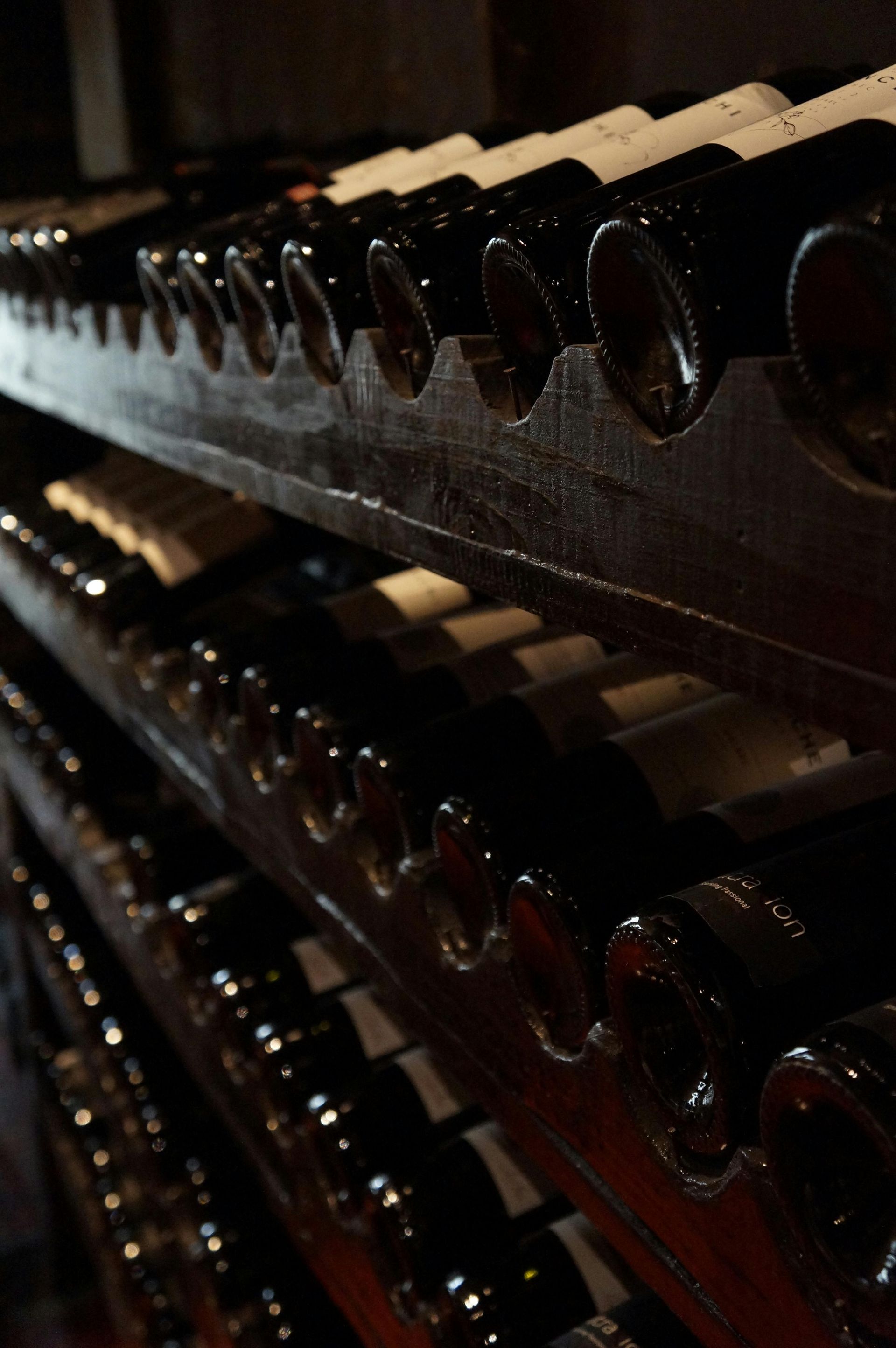 A row of wine bottles are lined up on a shelf