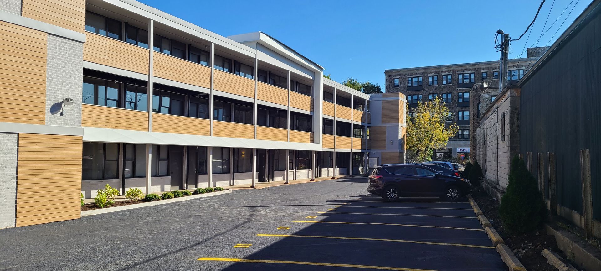 A parking lot in front of a large building with cars parked in front of it.