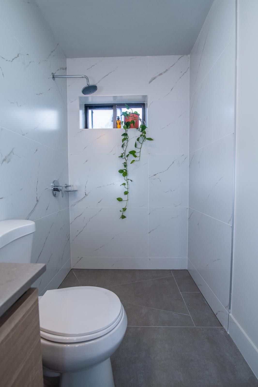 A bathroom with a toilet , sink and shower.