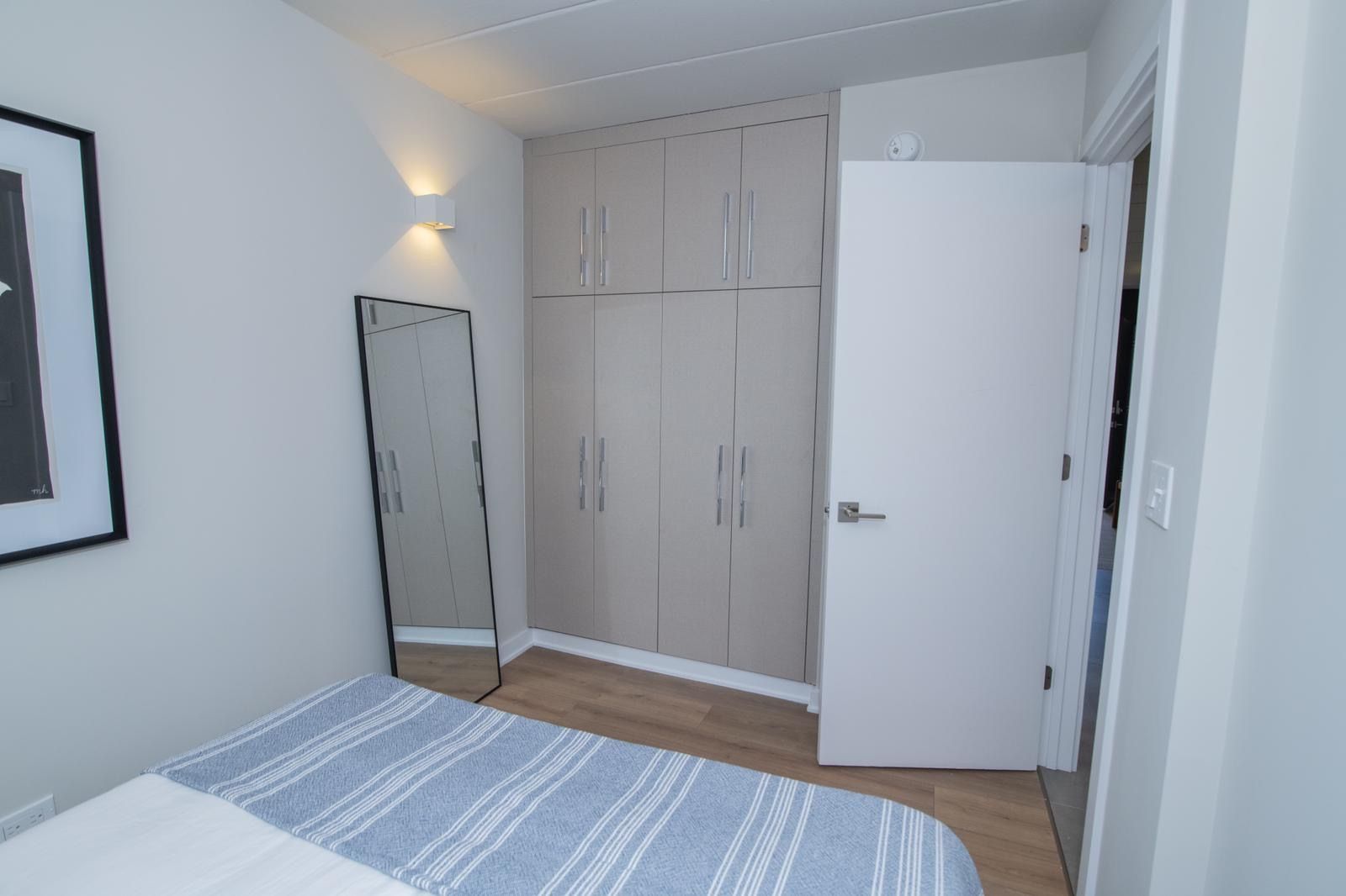 A bedroom with a bed , mirror and closet.