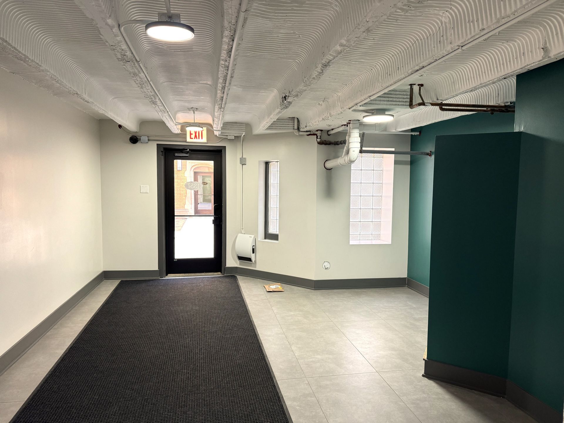 An empty hallway with a black rug and a door.